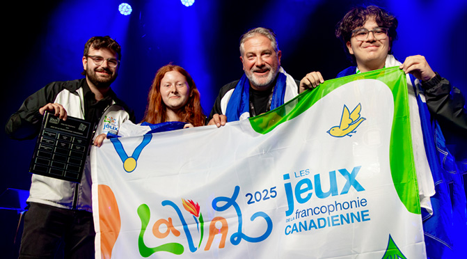4 personnes tenant le Drapeau gagnant aux Jeux de la francophonie canadienne 2025.